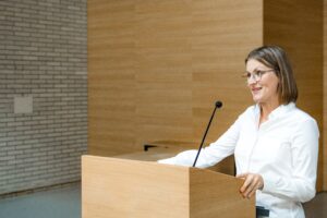 Frau steht am Rednerpult und hält eine Rede