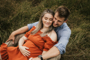 Babybauch, Pärchen sitzt und umarmt sich